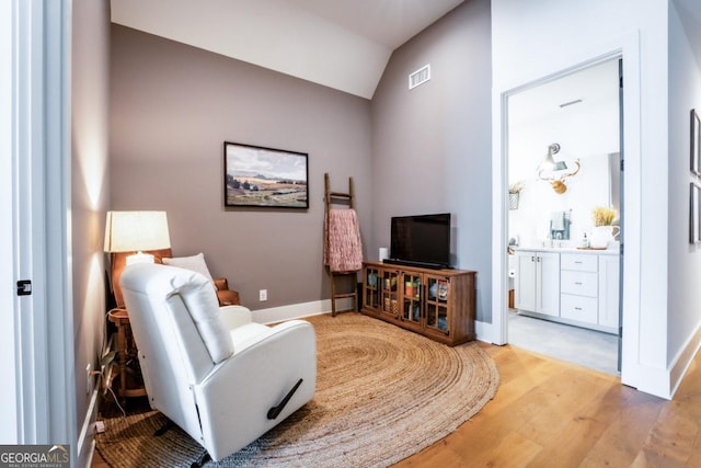 sitting room with visible vents, lofted ceiling, light wood-style floors, and baseboards