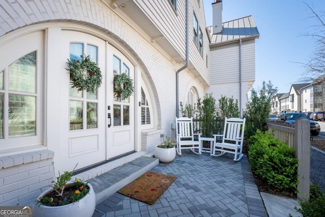 doorway to property featuring metal roof, brick siding, a chimney, and a standing seam roof