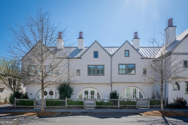 view of front of house featuring a fenced front yard, french doors, metal roof, and a standing seam roof