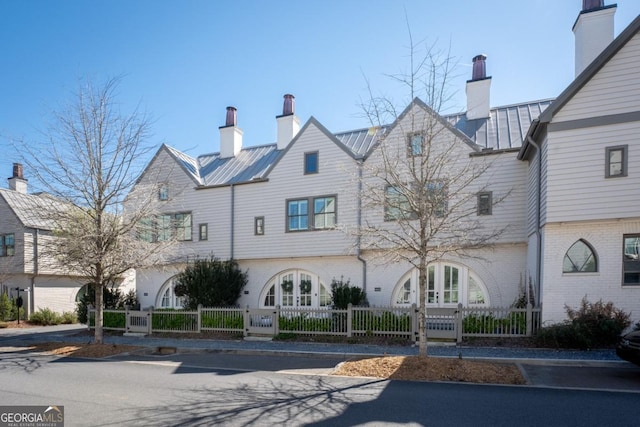 view of front of house featuring a standing seam roof, french doors, a fenced front yard, and metal roof