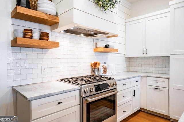 kitchen with stainless steel gas range oven, white cabinetry, tasteful backsplash, and open shelves