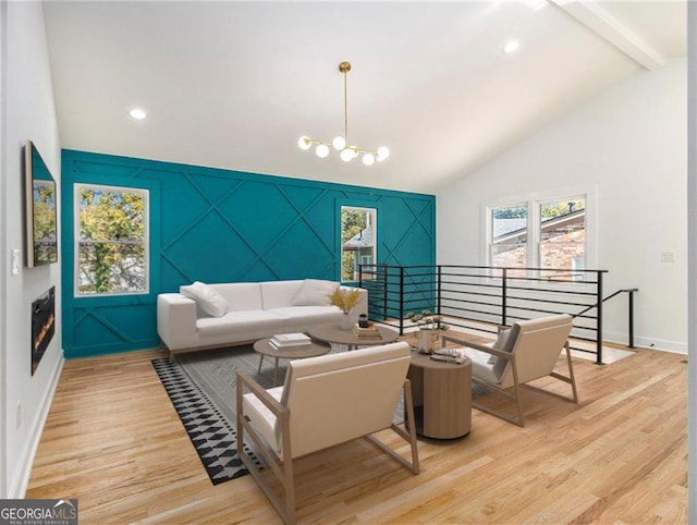 living room featuring baseboards, an inviting chandelier, light wood-style flooring, an accent wall, and beamed ceiling