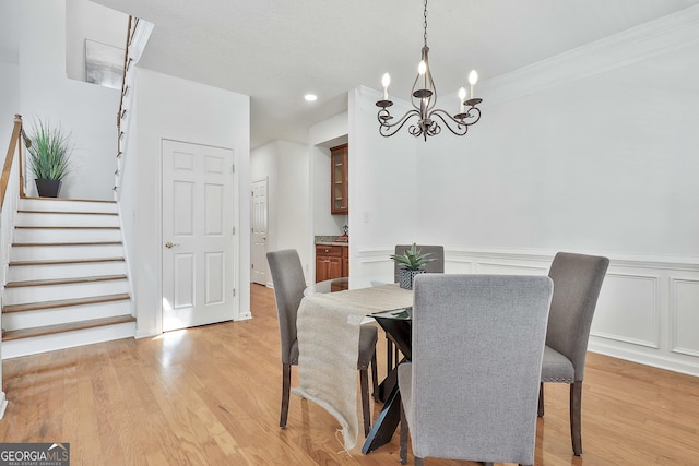 41 Eastlake Lndg, Newnan, GA 30265 - dining space with a chandelier, a wainscoted wall, stairs, light wood-type flooring, and ornamental molding