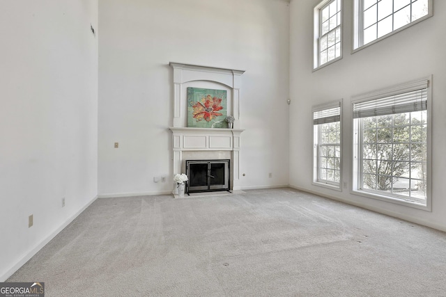 41 Eastlake Lndg, Newnan, GA 30265 - unfurnished living room featuring a towering ceiling, carpet floors, plenty of natural light, and a fireplace with flush hearth