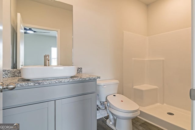 bathroom featuring vanity, toilet, wood finished floors, and a stall shower