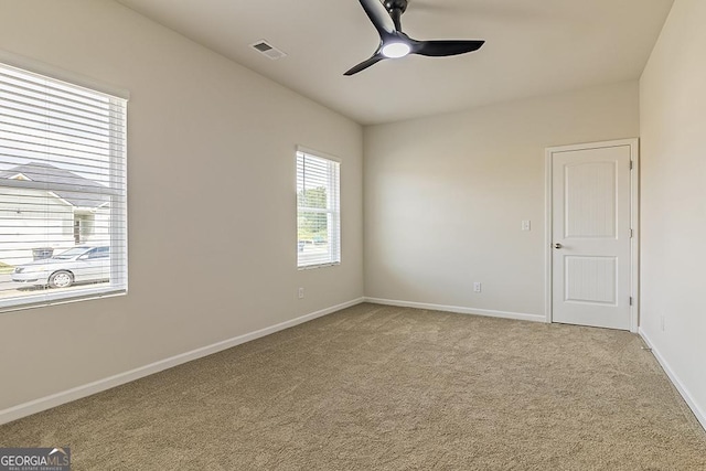 spare room with visible vents, baseboards, light colored carpet, and a ceiling fan