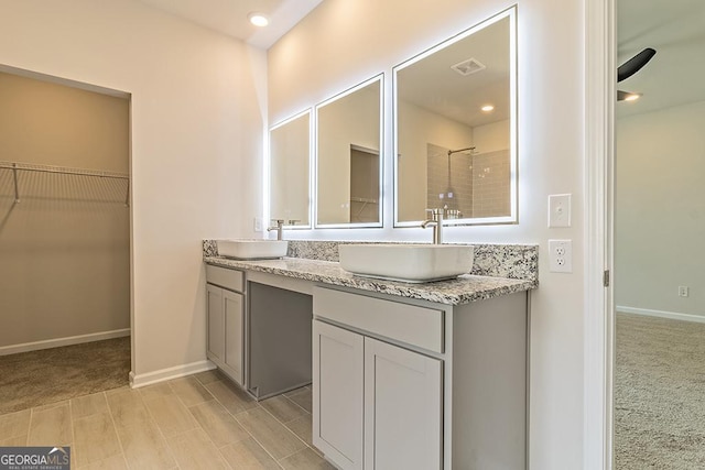 bathroom with a walk in closet, double vanity, visible vents, and a sink