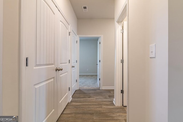 hallway featuring visible vents, baseboards, and dark wood-style floors