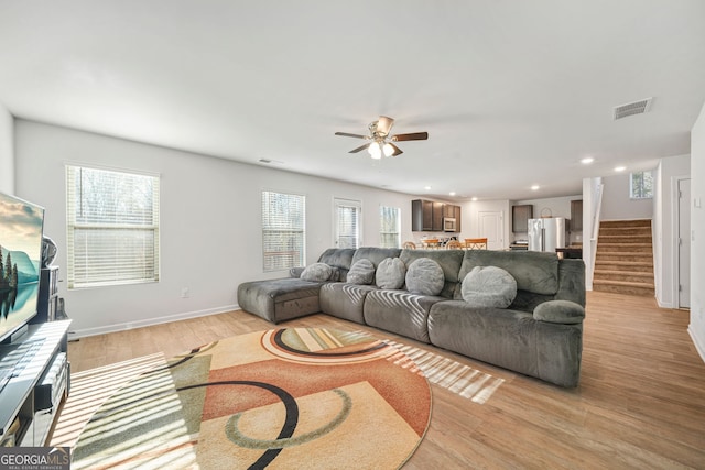 living area featuring stairs, a wealth of natural light, visible vents, and light wood finished floors