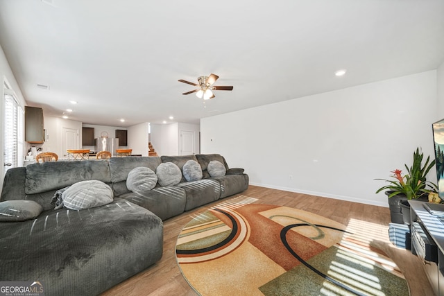 living room with light wood-type flooring, a ceiling fan, recessed lighting, stairway, and baseboards