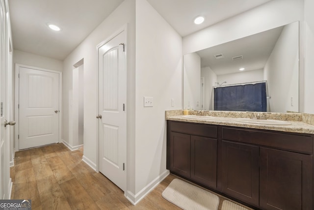 bathroom with double vanity, wood finished floors, visible vents, and a sink