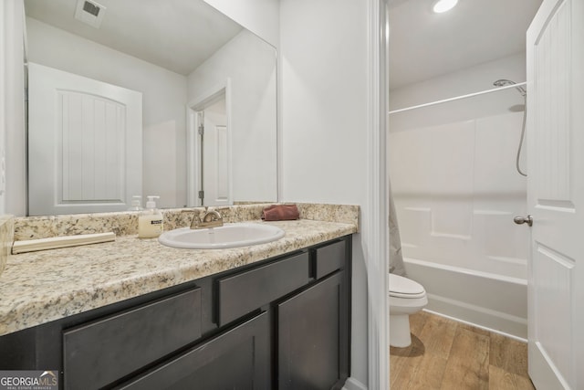 full bath with visible vents, toilet, shower / bath combo, wood finished floors, and vanity