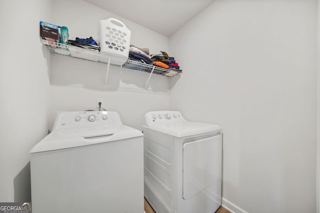 washroom featuring laundry area, baseboards, and separate washer and dryer