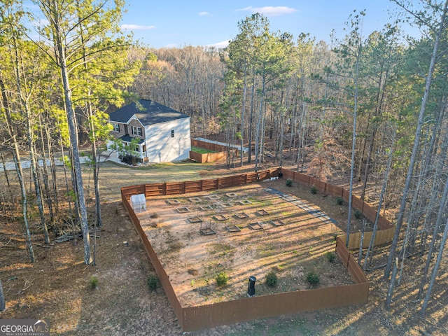 view of yard featuring a wooded view and fence