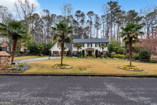 view of front of house featuring driveway, a garage, and a front lawn