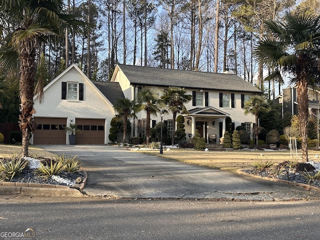 view of front of house with driveway, a chimney, a garage, and a shingled roof