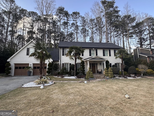 view of front of property featuring driveway, an attached garage, a front lawn, and a shingled roof