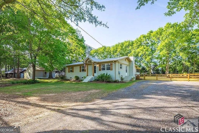 view of front of property featuring gravel driveway, a front lawn, and fence