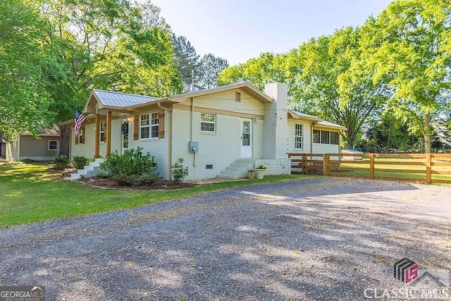 single story home featuring entry steps, fence, a front yard, brick siding, and a chimney