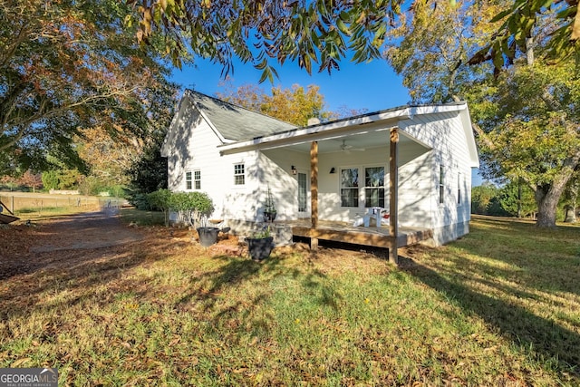 rear view of house featuring a lawn and a ceiling fan