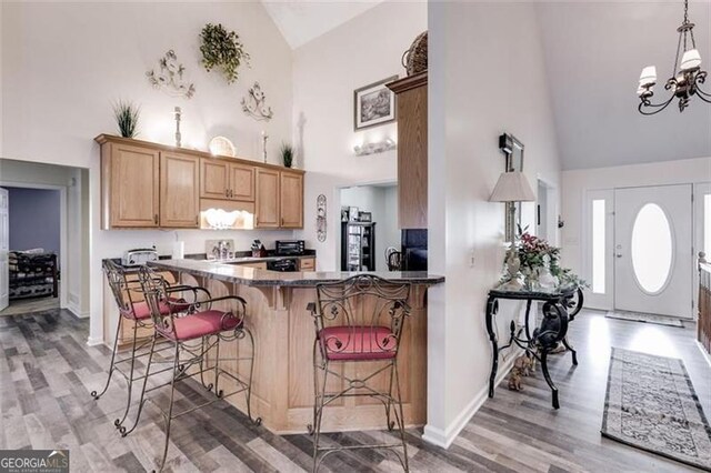 144 Bobs Dr, Mableton, GA 30126 - kitchen featuring baseboards, light wood finished floors, high vaulted ceiling, an inviting chandelier, and a kitchen breakfast bar