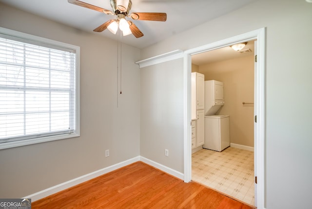 1650 Pierce Dairy Rd, Madison, GA 30650 - unfurnished bedroom featuring stacked washing maching and dryer, baseboards, multiple windows, and light wood-style floors