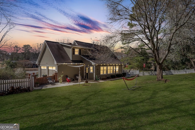 back of property featuring fence, a patio area, and a lawn