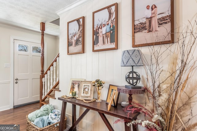 interior space featuring ornamental molding, a textured ceiling, wood finished floors, stairway, and baseboards