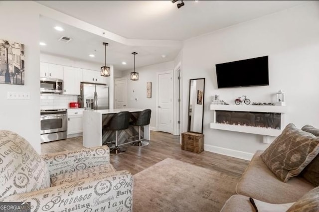 living room with light wood finished floors, visible vents, baseboards, recessed lighting, and a fireplace