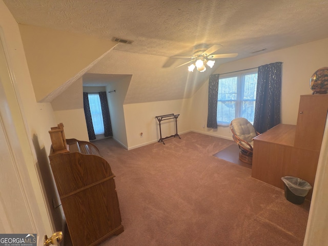 interior space featuring a ceiling fan, carpet, visible vents, lofted ceiling, and a textured ceiling