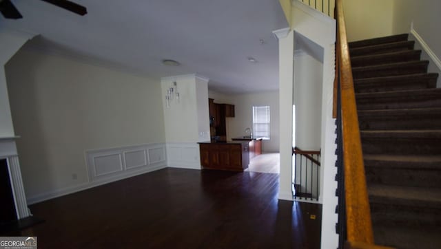 stairs with a wainscoted wall, wood finished floors, a ceiling fan, and a decorative wall