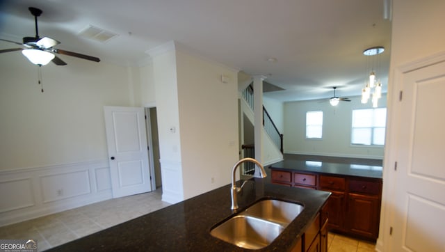 kitchen featuring a ceiling fan, visible vents, a sink, wainscoting, and a decorative wall