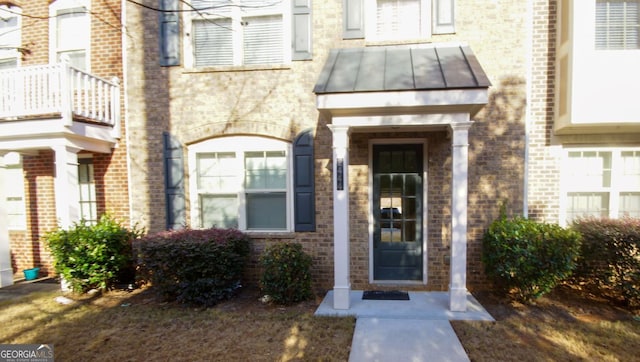 doorway to property with brick siding, metal roof, and a standing seam roof