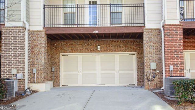 garage with central air condition unit and concrete driveway