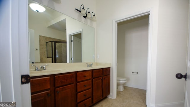 bathroom featuring double vanity, a shower stall, toilet, and a sink