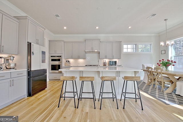 kitchen with decorative backsplash, double oven, light countertops, and freestanding refrigerator