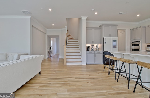 kitchen with visible vents, a breakfast bar, gray cabinets, light countertops, and double oven