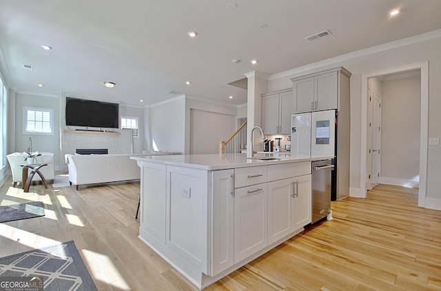 kitchen featuring visible vents, a sink, refrigerator, light wood-style floors, and light countertops