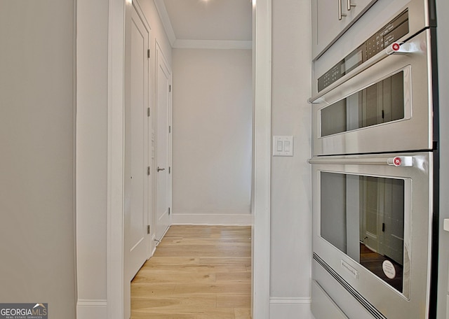 corridor with crown molding, light wood-style floors, and baseboards