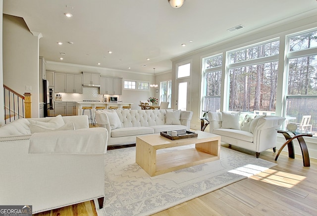 living room with stairway, visible vents, recessed lighting, ornamental molding, and light wood-type flooring