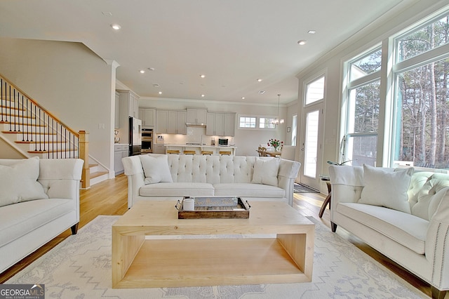 living room featuring crown molding, stairway, recessed lighting, and light wood finished floors