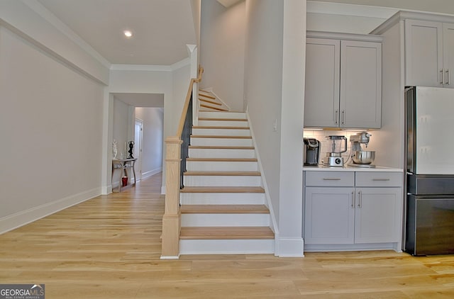 stairs with recessed lighting, wood finished floors, baseboards, and ornamental molding