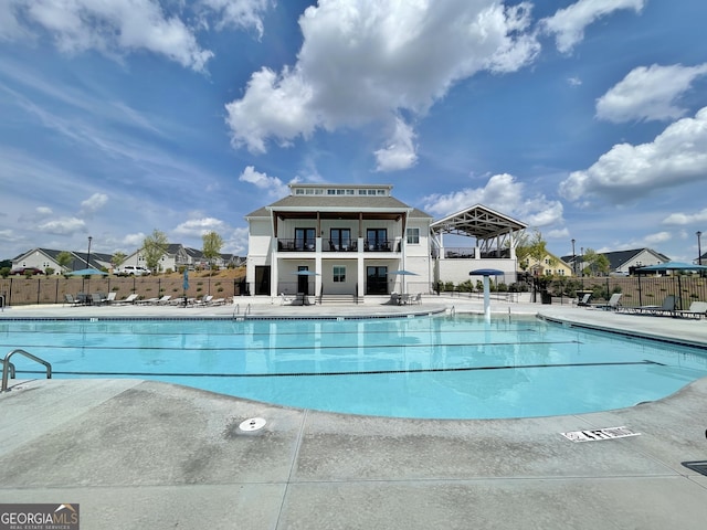 community pool with a patio area and fence