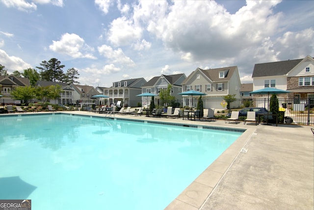 community pool with a residential view, a patio, and fence