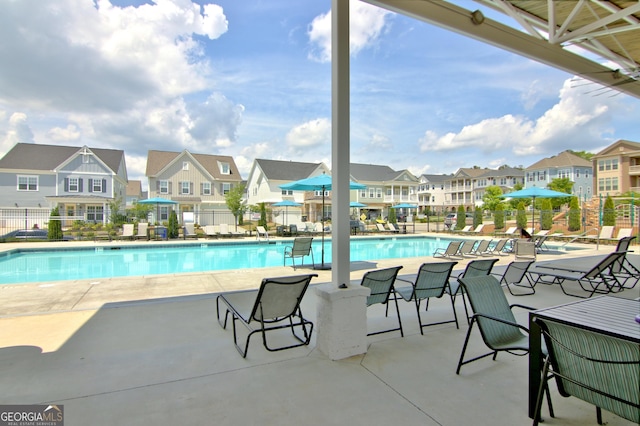 community pool featuring a residential view, a patio, and fence