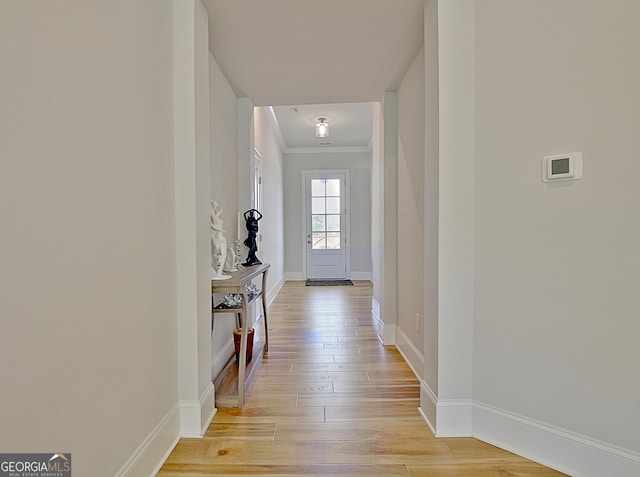 hallway featuring light wood-type flooring, baseboards, and crown molding