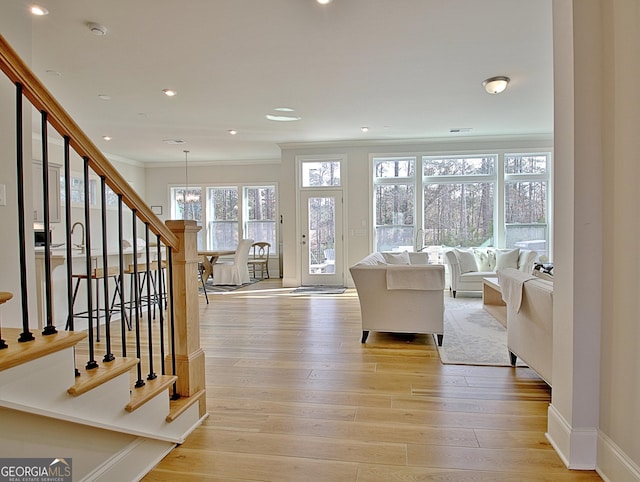 living room featuring recessed lighting, stairway, crown molding, light wood finished floors, and baseboards