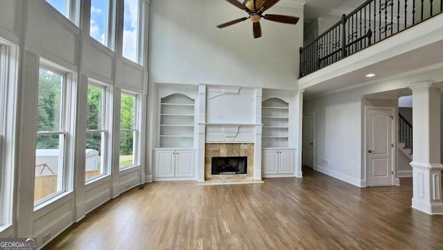 838 Natchez Valley Trce NE, Grayson, GA 30017 - unfurnished living room with a towering ceiling, ceiling fan, wood finished floors, plenty of natural light, and a tile fireplace