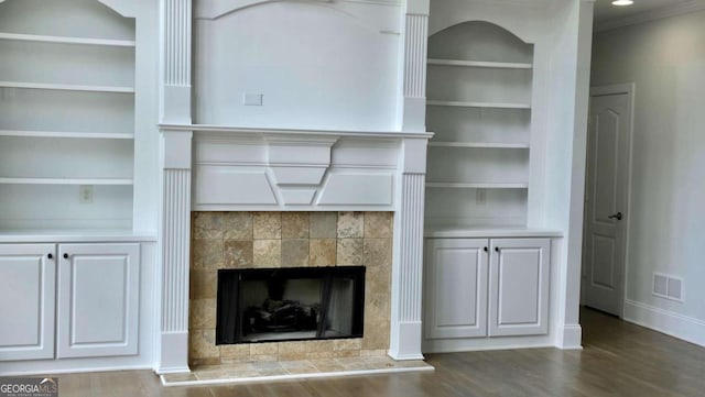 838 Natchez Valley Trce NE, Grayson, GA 30017 - unfurnished living room with built in shelves, wood finished floors, a tiled fireplace, and crown molding