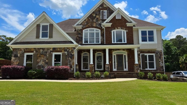 craftsman inspired home featuring stone siding, a shingled roof, and a front yard